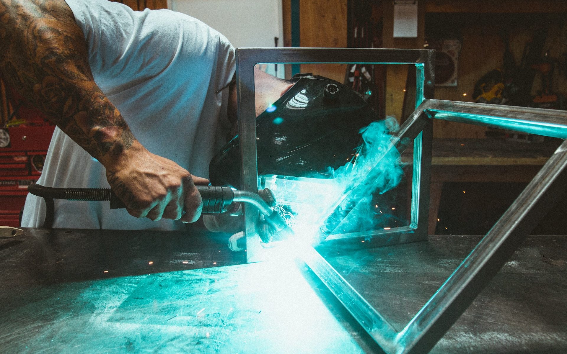 man welding two rectangular gray metal frames